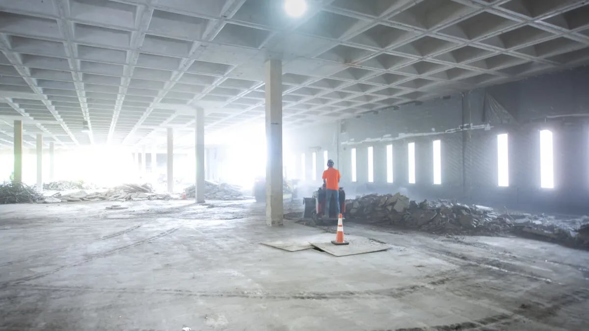 A man standing in a warehouse that is in the process of being renovated