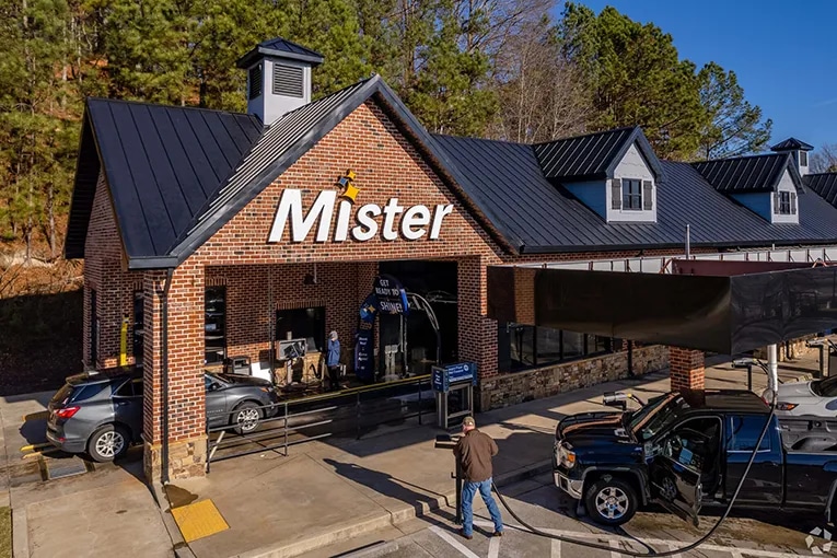 Mister cash wash exterior view showing their tunnel car wash and customers in view