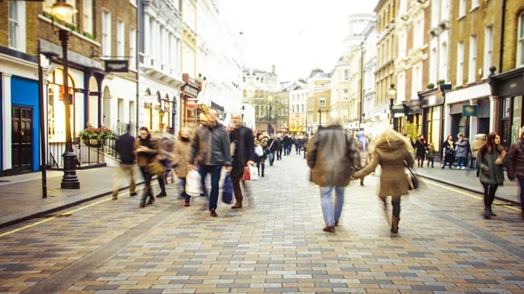 A busy city street with people walking towards and away from the camera