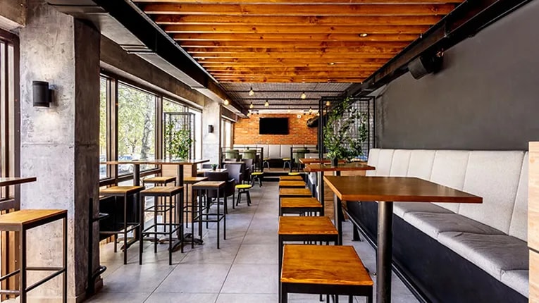 Interior view of a restaurant with high tables on the left side and booths on the right side