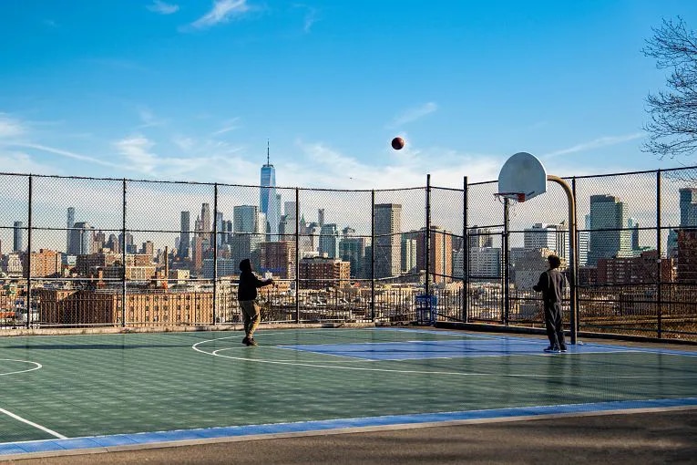 People playing basketball in The Heights, NJ, with NYC skyline as the backdrop