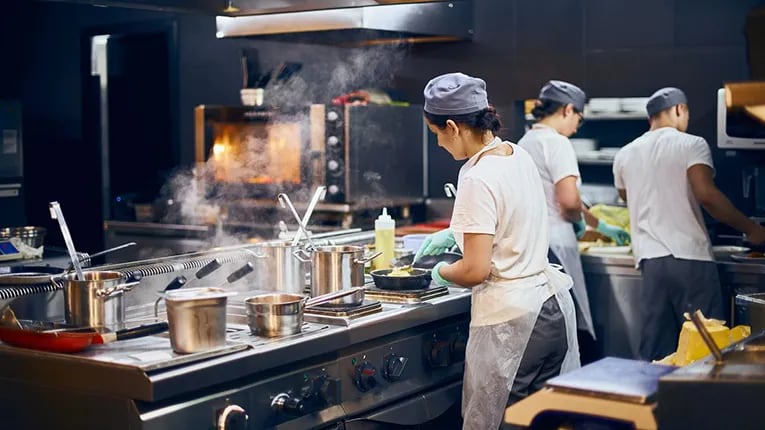 A commercial kitchen with three cooks working