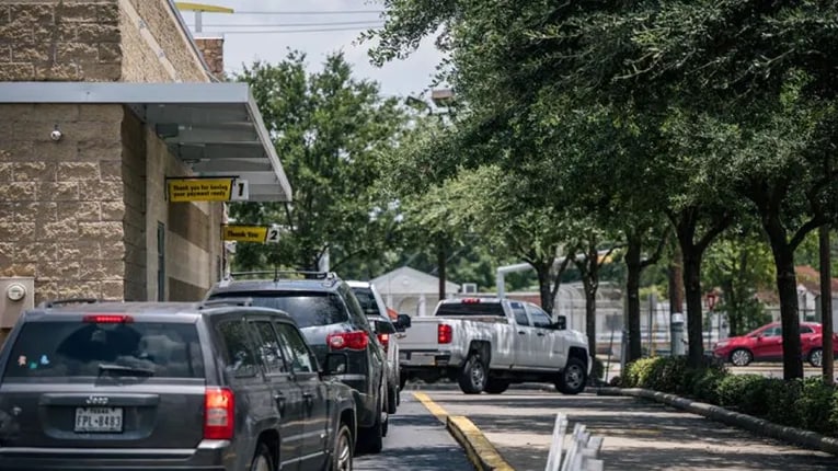 Customers ordering and picking up food at a drive-thru.