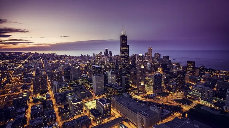 A cityscape at night with the ocean in the background