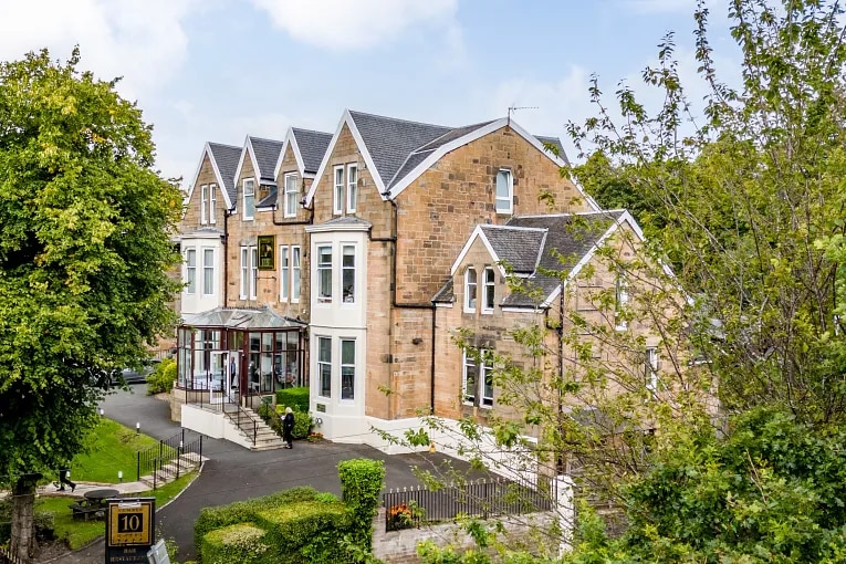 Exterior view of a hotel in Glasgow, Uk with trees around the building