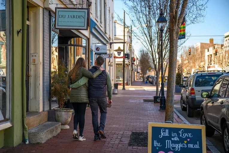 A couple walking in front of retail shops in Fredericksburg, VA.