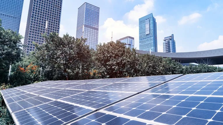 Top of a building showing solar panels with skyscraper in the background